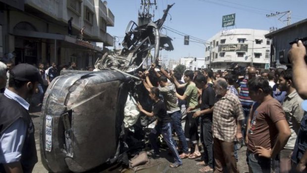 People gather around a vehicle, believed to have carried Hamas members, that was targeted in an Israeli airstrike on Gaza City. Four people were killed, medics said.