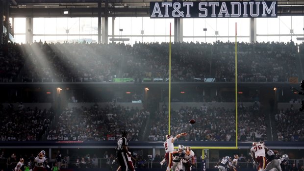 Picturesque: The sun shines through the windows at AT&amp;T Stadium as Kirk Cousins releases a pass.