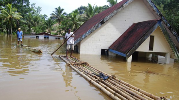 Residents paddle through flooded Wailotua village in Fiji.