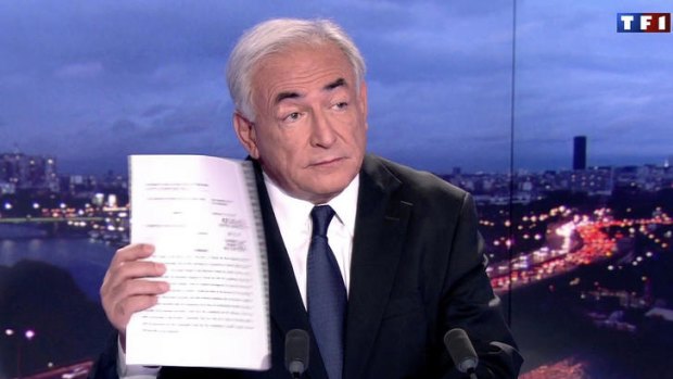 Dominique Strauss-Kahn defiantly brandishes the prosecutor's report that put an end to his trial on charges of sexually assaulting a hotel maid.