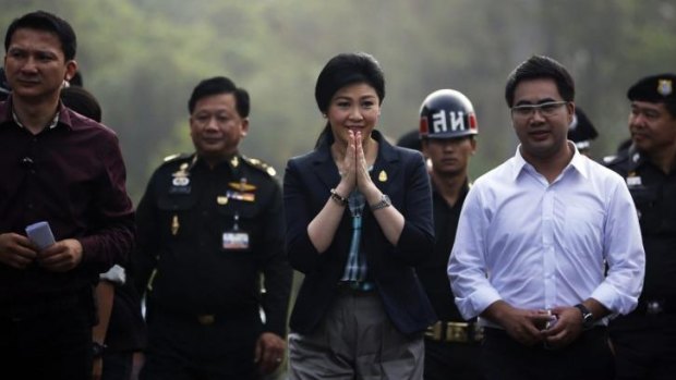 Prime Minister Yingluck Shinawatra, centre, greets people as she arrives to a polling station to cast her vote.