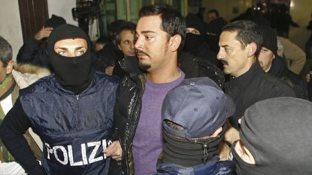 Masked officers escort Gianni Nicchi to a police station.