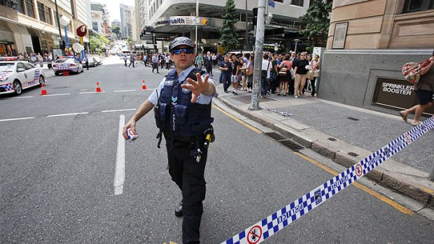 A police officer keeps back crowds during the siege in Queen Street Mall.