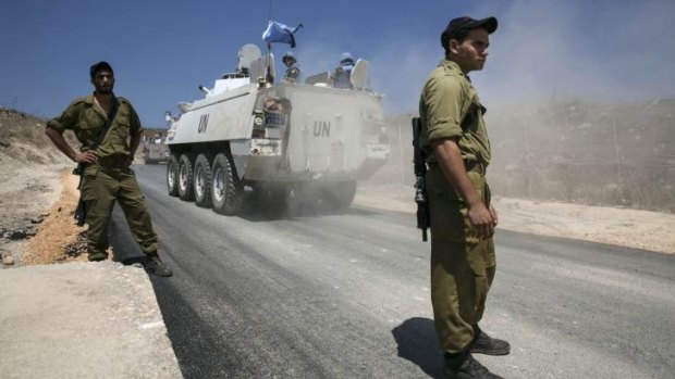 Israeli soldiers watch as UNDOF vehicles cross into Syria from the Israeli-occupied sector of the Golan Heights.