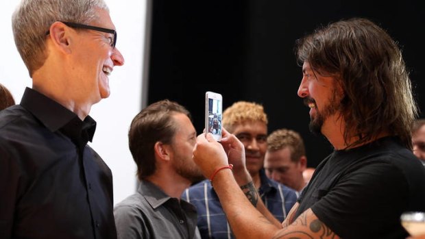 Apple CEO Tim Cook looks on as Dave Grohl of the Foo Fighters looks at the new iPhone 5.