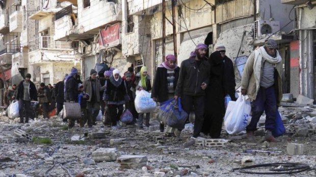 'Heart of the revolution': Civilians carry their belongings as they walk towards a meeting point to be evacuated from Homs.
