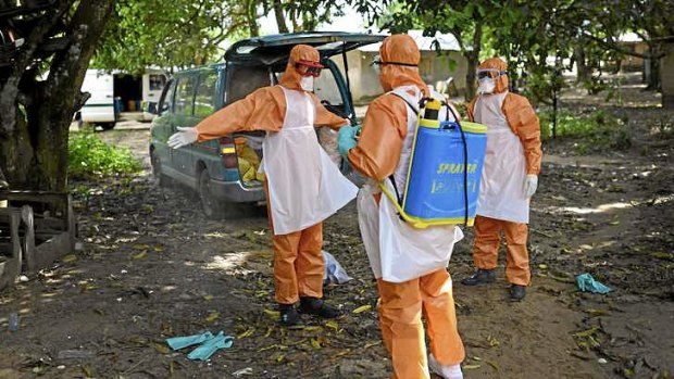 Members of a burial team spray themselves with chlorine after removing the body of a suspected Ebola victim from a home in Waterloo, Sierra Leone.