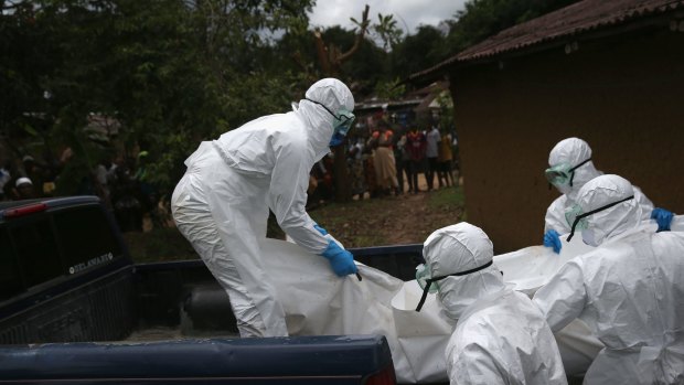 A burial team from the Liberian Red Cross carries the body of an Ebola victim from his home near Monrovia, Liberia. 