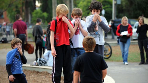 Children take impromptu health measures as their worried parents arrive at Clifton Hill Primary School yesterday.