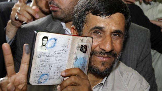 President Mahmoud Ahmadinejad holds his passport while flashing the victory sign after casting his ballot for the Iranian presidential election in Tehran.