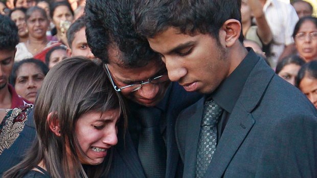 Jacintha Saldanha's widower Ben Barboza, centre, and her children Lisha, left, and Junal mourn during her funeral at a cemetery in Shirva in December.