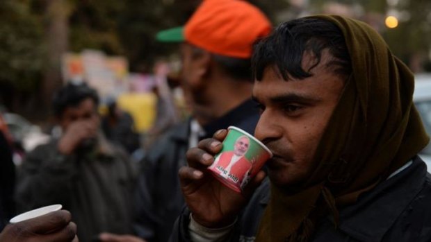 A pedestrian sips tea from a cup bearing the portrait of prime ministerial candidate Narendra Modi.