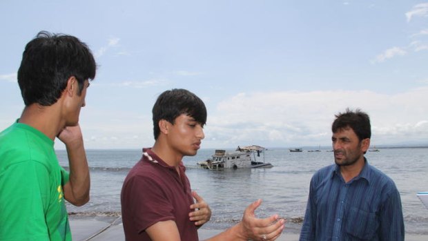 Pakistani asylum seekers, from left, Zamin Hussain, 25,   Kamran Haider, 17 and Lal Muhammad, 17,  in front of the sunken vessel at Pangandaran, West Java