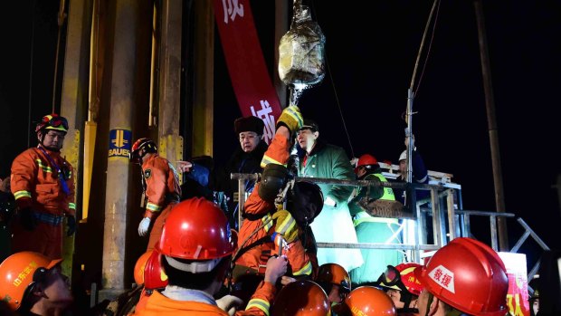 50-year-old miner Zhao Zhicheng, centre on hoist, is lifted from a collapsed mine in Pingyi after spending 36 days 200 metres underground.