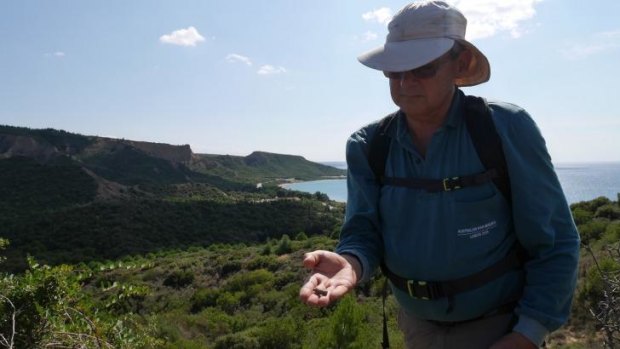 Rear Admiral Simon Harrington, manager of Australia’s study team, examines an archaeological find with ANZAC Cove and The Sphinx in the background.