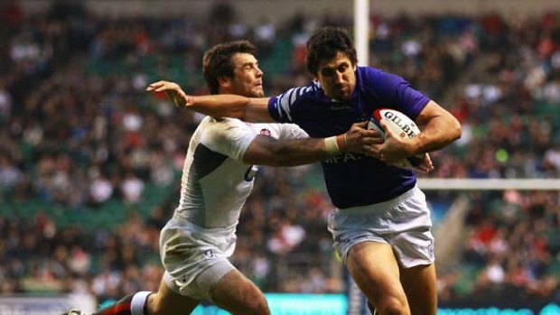 Paul Williams of Samoa (R) scores a try despite the tackle from Ben Foden.