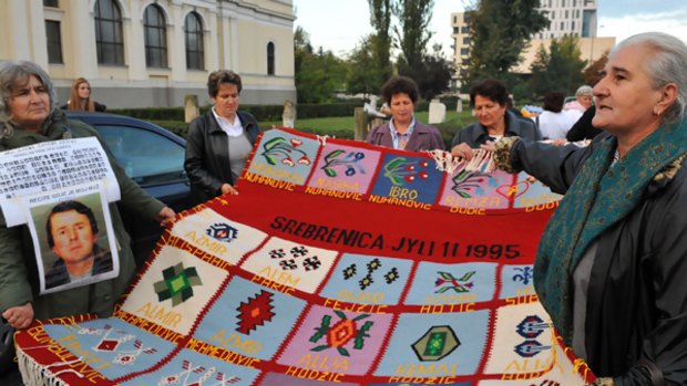 Bosnian Muslim women from Srebrenica hold a hand-woven carpet embroidered with the names of their slain relatives before leaving for The Hague.