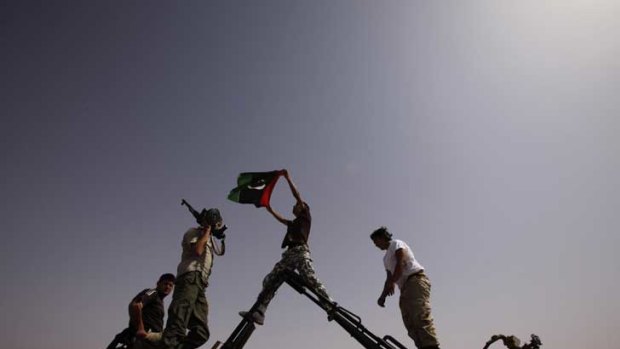 Rebels hold up a kingdom of Libya flag at the last checkpoint before the town of Bani Walid, held by pro-Gaddafi forces.