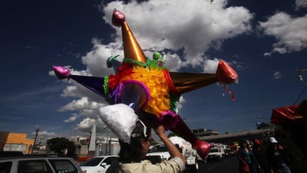 December is awash with reasons to  celebrate  in Mexico. A man carries a traditional Christmas pinata on his head.