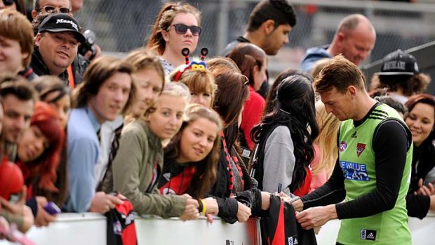 Essendon's Brendon Goddard signs autographs for with fans during training on Friday.