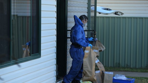 A NSW Forensic officer carries evidence bags into the backyard of Vincent Stanford's home.