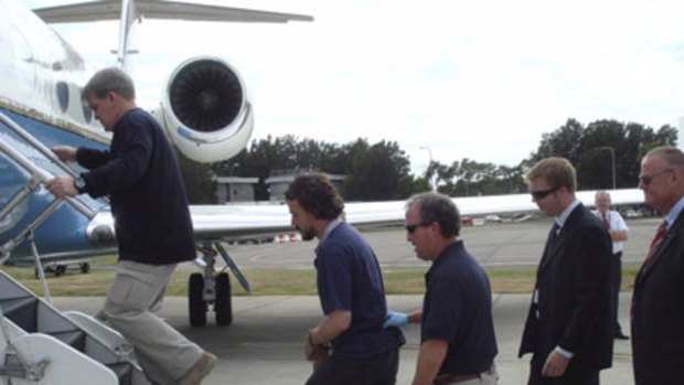 Homeward bound ... a handcuffed Laurence Rivera is led on to a "Con Air" flight.