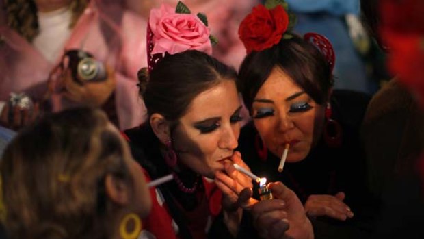 Women in traditional dress light their cigarettes on New Year's Eve in Coin, near the southern Spanish town of Malaga.