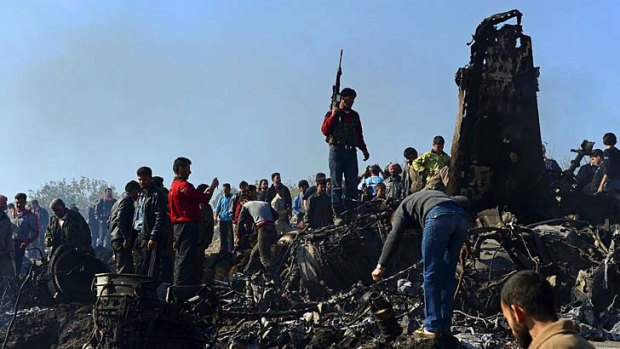 Syrian rebels and civilians gather around the remains of a Syrian government fighter jet.