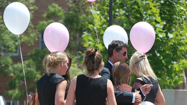 Grace Anne Cuzens is surrounded by friends and family as they prepare to release balloon at the memorial service for her younger sisters Jessica and Jane.