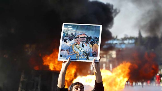 Burning desire for change ... a protester holds up a placard of Muammar Gaddafi in Tripoli.