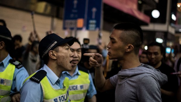 Tension ... Police officers argue with a man after he and others attacked pro-democracy protesters in the Causeway Bay district of Hong Kong.
