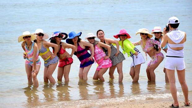 Tourists pose for photos on a beach in Bali. The island has bounced back and hosting the world's leaders for APEC shows the popular destination is now on a high.