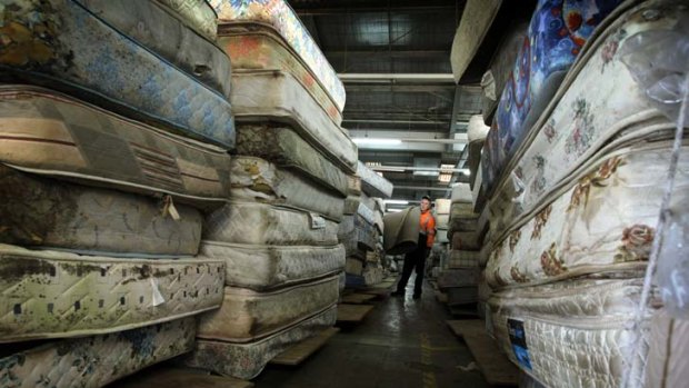 Cushioning the blow of waste management ... Michael Lamb stands among some of the hundreds of mattresses used by Mission Australia in a recycling program.