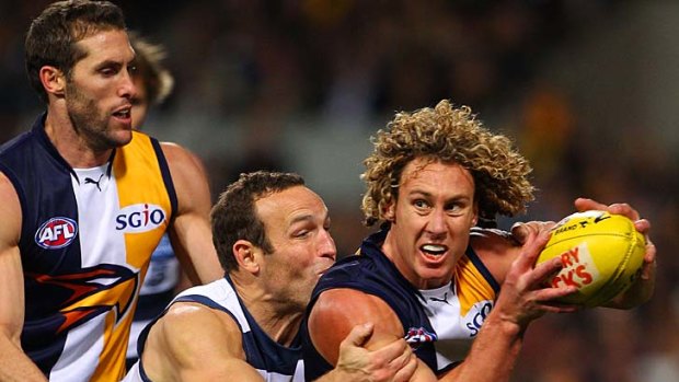 Eagle Matt Priddis looks to break a tackle by Brad Ottens of the Cats.