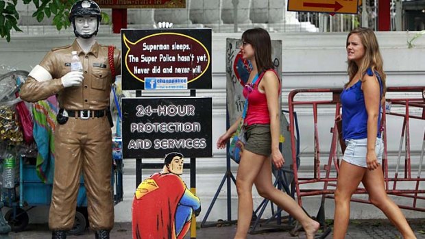 Tourists walk pass a cut-out cardboard figure of a tourist policeman along Khao San road in Bangkok. Questions are being raise over whether Thailand is squandering a prized asset by failing to protect travellers arriving in record numbers.
