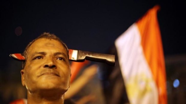 A supporter of Egypt's former army chief Abdel Fattah al-Sisi wears a fake knife over his head in front of an Egyptian flag as he celebrates at Tahrir square in Cairo.