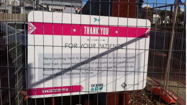 A sign has been put up on fencing reassuring people that the artwork is not finished yet.  