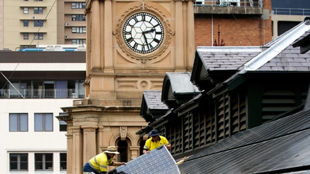 Raising the roof … workers install solar panels on the Town Hall yesterday.
