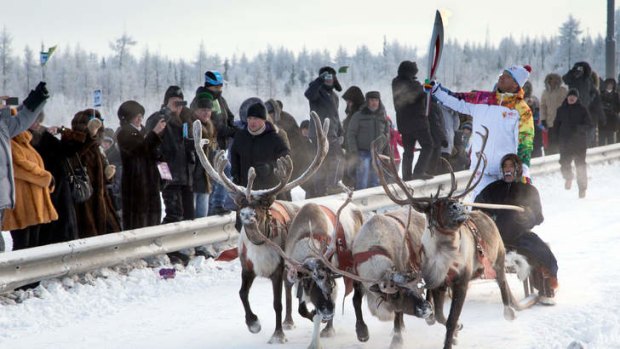 The Sochi 2014 Winter Olympic torch is carried by a torchbearer riding atop a deer sleigh in the West Siberian town of Novy Urengoy, 2342 km north-east of Moscow.