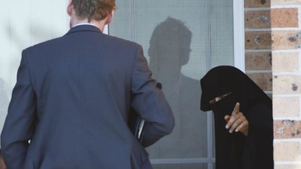 A woman talks to police at a house in Guildford.