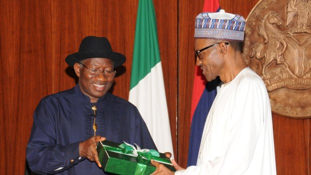 Goodluck Jonathan (left) presents a gift to Muhammadu Buhari at the presidential villa in Abuja, Nigeria.