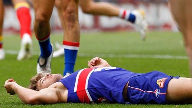Bulldogs midfielder Callan Ward lies on the ground after an encounter with Campbell Brown.
