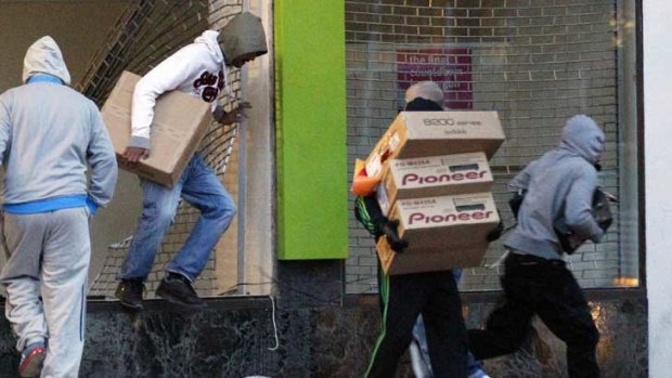 Looters carry boxes out of a home cinema shop in central Birmingham.