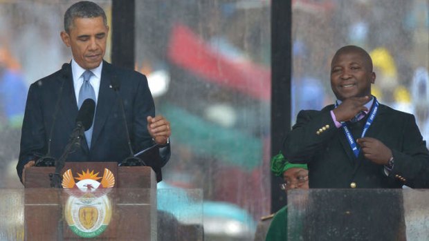 All smiles ... US President Barack Obama delivers a speech next to the fake sign language interpreter during the memorial service for late South African President Nelson Mandela in Johannesburg.
