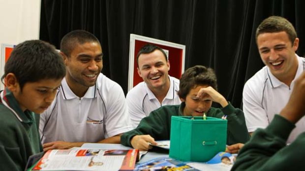 Money well spent ... Souths players, from left, Nathan Merritt, Beau Champion, and Sam Burgess with pupils from Dubbo at a special classroom in Alexandria yesterday.