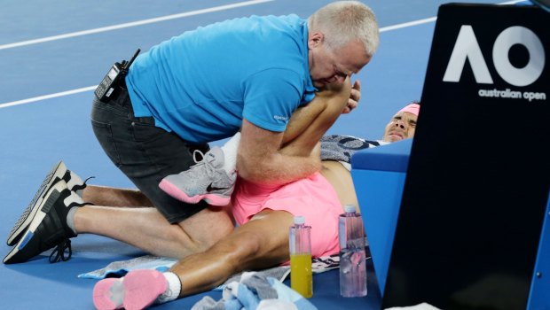 Rafael Nadal grimaces as receives treatment during the game.