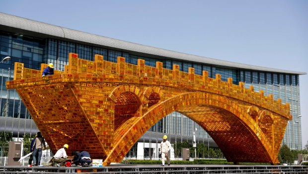 Workers install a 'Golden Bridge of Silk Road' structure outside China's Belt and Road Forum in Beijing in April.