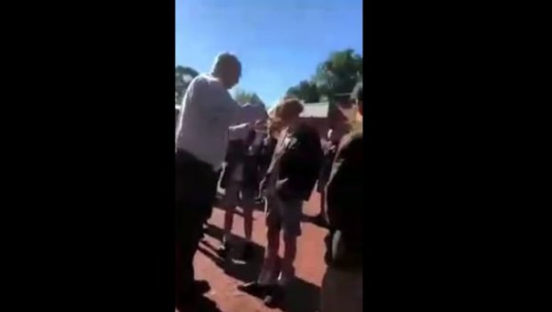 A screenshot from a video of Trinity's deputy principal cutting a student's hair.