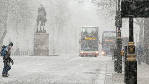 Pedestrians cross Whitehall as snow falls in London on Tuesday.