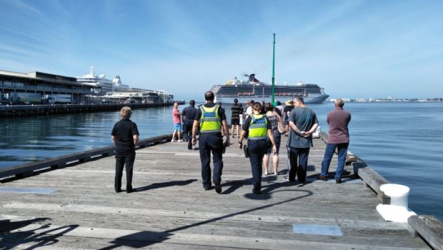 Onlookers and police waiting for the arrival of the Carnival Legend cruise ship at Melbourne's Station Pier  on Saturday.